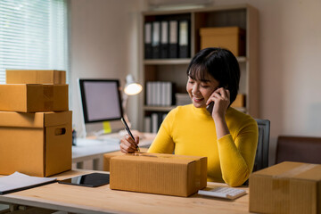 woman is talking on her cell phone while writing on a box