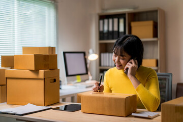 woman in a yellow shirt is talking on her cell phone while writing in a box