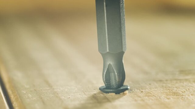 Close-up black self tapping screw unscrewing from wooden surface. Macro view hardware fastener backing out of timber on repair. Dark metal screw working out of wood during construction