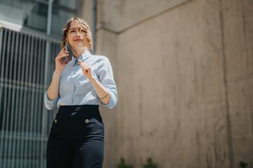 Person wearing formal attire engages in a phone conversation outdoors against a modern, urban background, conveying focus, confidence, and effective communication in a workplace or business scenario.