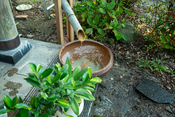 Japanese garden bamboo spout pouring water into stone basin