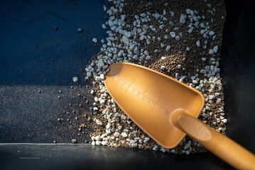 Gardening scoop mixing pumice and soil in container
