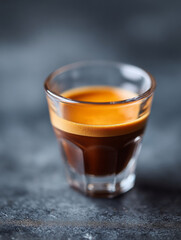 Dark rich espresso shot in clear glass cup offers an invigorating and delicious start
