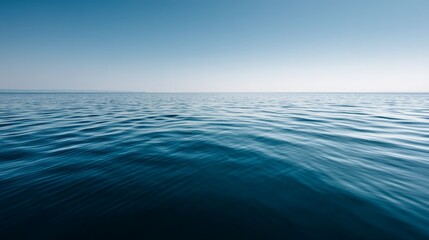Fototapeta premium Calm blue water surface with gentle ripples under clear sky, peaceful nature scene with copy space on left, wideangle view