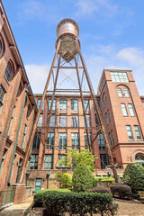 Vertical Low-angle view of a tall brick industrial building featuring a prominent metal water tower.
