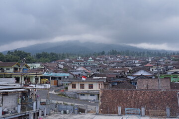 Sunday, August 3, 2025, 14.20.52, Temanggung, Indonesia _ Traditional Village nestled against the backdrop of mountains, with a cloudy sky above