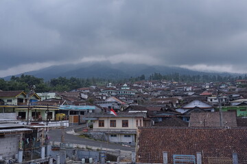 Obraz premium Sunday, August 3, 2025, 14:20:52, Temanggung, Indonesia _ Misty Mountain Village A Scenic View of Houses nestled beneath Cloudy Peaks