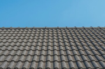 Abstract design of a house with grey mosaic tile roofing under a clear blue sky