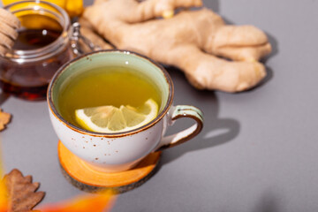 Cup of hot tea with ginger, honey and lemon on the grey background