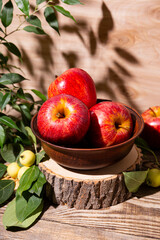 Ripe red apples in a bowl and small green apples on a wooden background, apple harvest concept