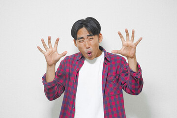 Young man with surprised expression, hands outstretched, against a plain background.