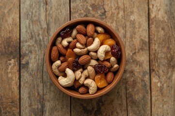 Assorted dried fruits and savory nuts served in a bowl placed on a wooden table