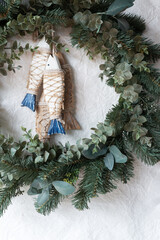 green Christmas wreath with wooden fish decoration on paper texture background.