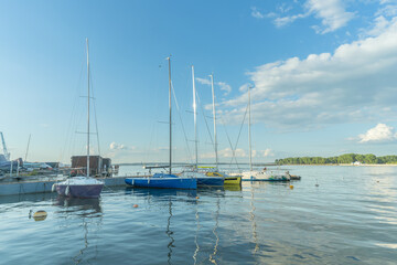 Obraz premium Sailboats docked at quiet marina under clear blue sky. Yachts moored quietly in the harbor, poised for new journeys beneath an endless sky of freedom and possibility.