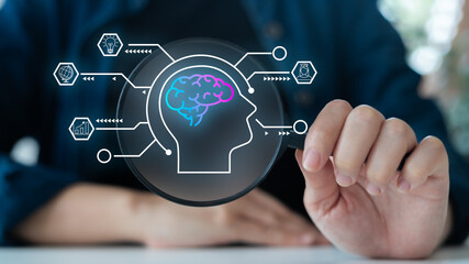 Hand holding magnifying glass with hologram brain and innovation icons, symbolizing artificial...