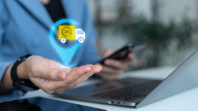 Businesswoman holding hologram truck with 24h icon and location pin, symbolizing online delivery service, fast shipping, e-commerce logistics, smart tracking system, and supply chain management.
