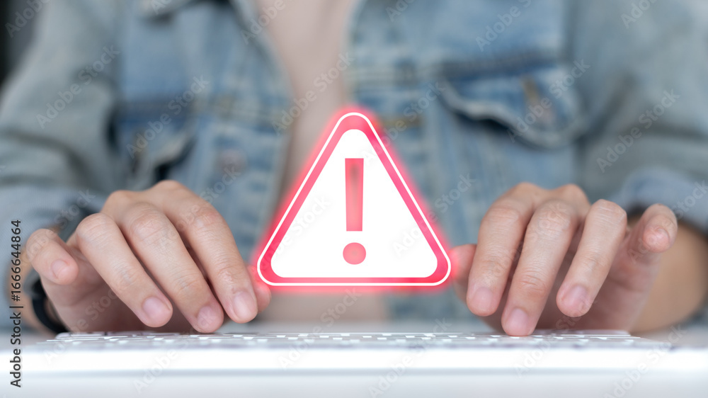 Poster hands typing on a keyboard with a warning alert icon, symbolizing cybersecurity risk, online threat,