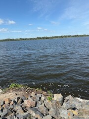 Scenic Riverbank with Rocky Shore under Blue Sky