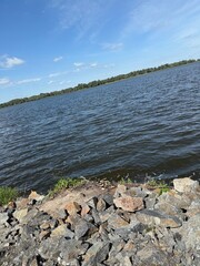 Scenic Riverbank with Rocky Shore under Blue Sky