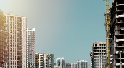 Architecture of modern city skyline with apartment towers, construction cranes and unfinished