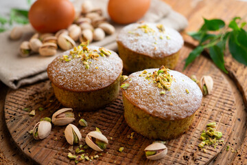 Pistachio muffins on a wooden surface.