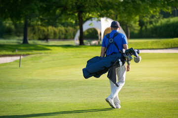 Golfer walking on the golf course carrying golf bag