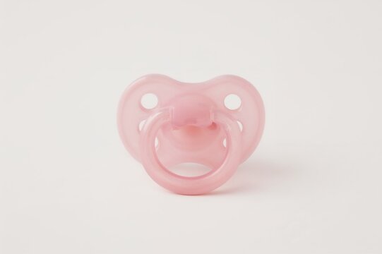 A pink silicone baby pacifier on a plain white backdrop