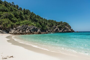 Fototapeta premium A tranquil shoreline featuring transparent waters, verdant rocky outcrops, and pristine white sands in a tropical setting.