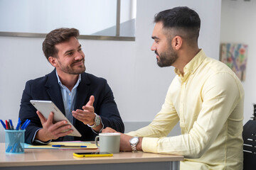 Office colleagues collaborating on project using tablet at desk