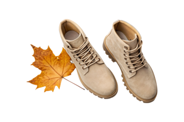 Light brown hiking boots paired with golden orange fall maple leaves decoration, isolated on a transparent background