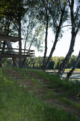 Fototapeta premium geometric concrete tower with concrete steps leading up to it against the backdrop of a river and forest