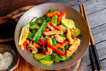 Asian food stir fried green peas with chicken and vegetables, sesame seeds in a bowl