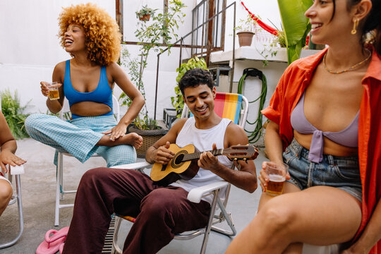 Brazilian friends playing cavaquinho and drinking together at summer gathering - Powered by Adobe