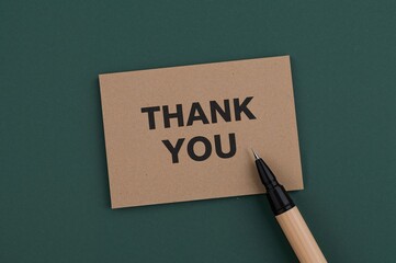 Gratitude message handwritten in black ink on a wooden crate with a dark green backdrop and empty space.