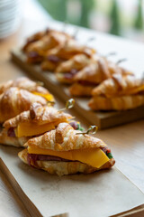 Freshly baked ham and cheese croissants arranged on a rustic wooden board