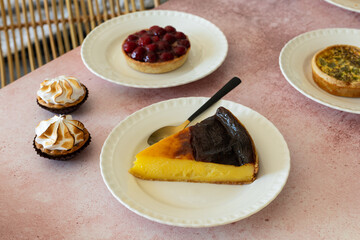 Table with French pastry, desserts, flan cake, mini meringue lemon tart and fruit tart.