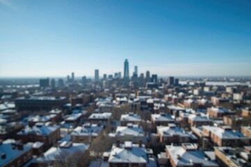 Fototapeta premium Out-of-focus cityscape showcasing contemporary buildings topped with snow under a clear blue winter sky.