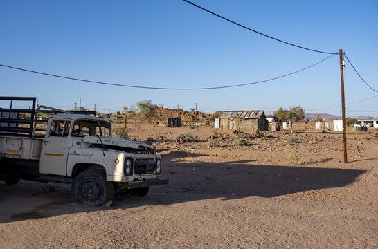 Old transport vehicle and simple houses made of wood and mud in a small village, Erongo, Damaraland, Namibia