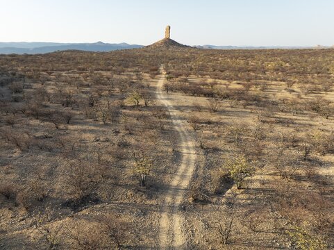 The Vingerklip (rock finger) is surrounded by thornbush and mopane (Colophospermum mopane) savanna. Aerial view. Drone shot. Damaraland, Namibia