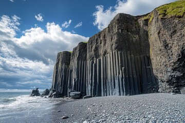 jagged basalt columns rising from a pebble beach