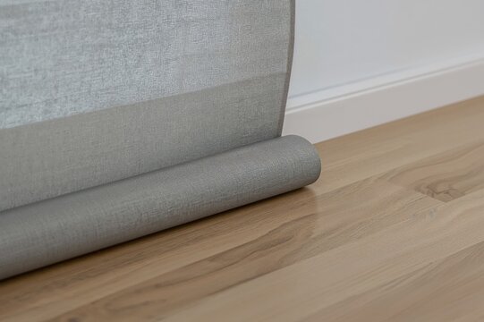 Close-up of gray fabric window shades resting on wooden flooring