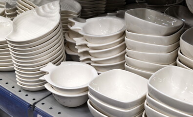 Collection of white ceramic bowls arranged on shelves in a home goods store, showcasing various...