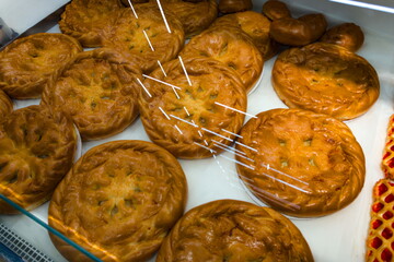 Freshly baked pastries displayed in a bakery case in the early morning sun, showcasing golden brown crusts and intricate designs