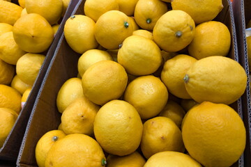 Fresh lemons stacked in wooden crates at a bustling market, showcasing vibrant yellow color and a variety of sizes during a sunny afternoon