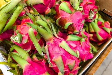 Brightly colored dragon fruit piled in a wooden crate at a vibrant market in the early morning sun inviting shoppers to explore unique tropical produce