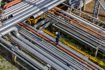 Male worker inspection at steel long pipes and pipe elbow in station oil factory during refinery valve of visual check record pipeline