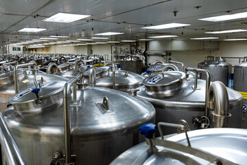 Stainless vertical steel tanks and pipes with pressure meter in equipment tank chemical cellar at...