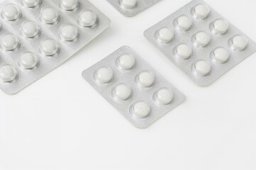 Various white tablets in blister packaging on a white surface. Medication for health maintenance, therapy, and prevention.
