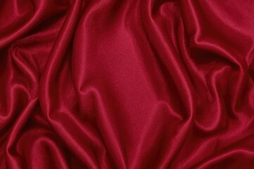 Fototapeta premium Deep burgundy silk satin backdrop with glossy creases on shimmering cloth. Opulent background featuring blank area for design. Aerial perspective web banner.
