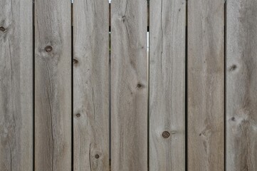 Fototapeta premium Textured old wooden fence with visible grain, nail marks, and knots in natural gray and brown shades, perfect for rustic and construction-themed designs.